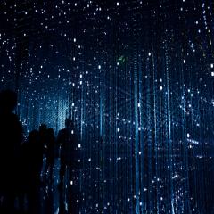 5 people standing in a dark room illuminated with square string lights 
